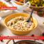 mashed potatoes in a yellow bowl, garnished with herbs, and a wooden spoon